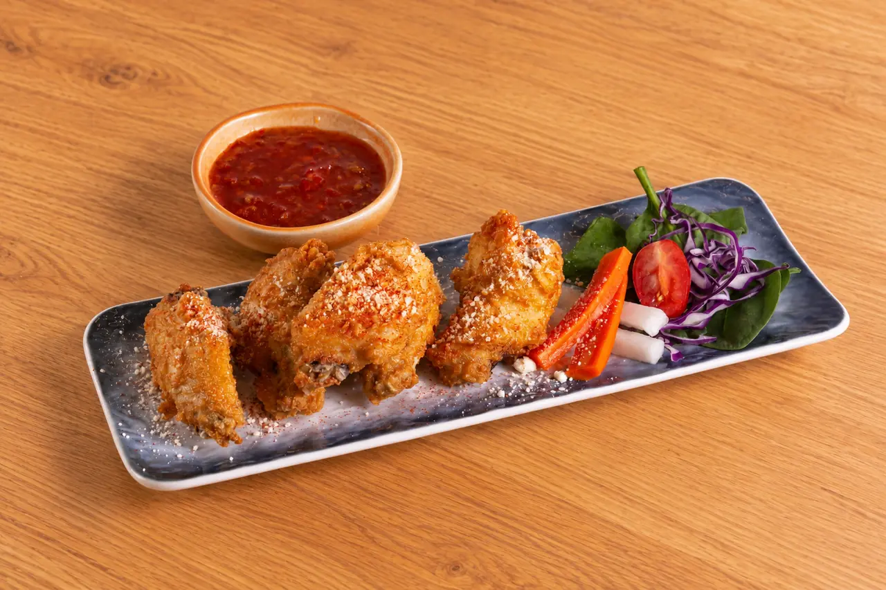 Larb-Dusted Crispy Wings with seasoning, salad garnish and dipping sauce.