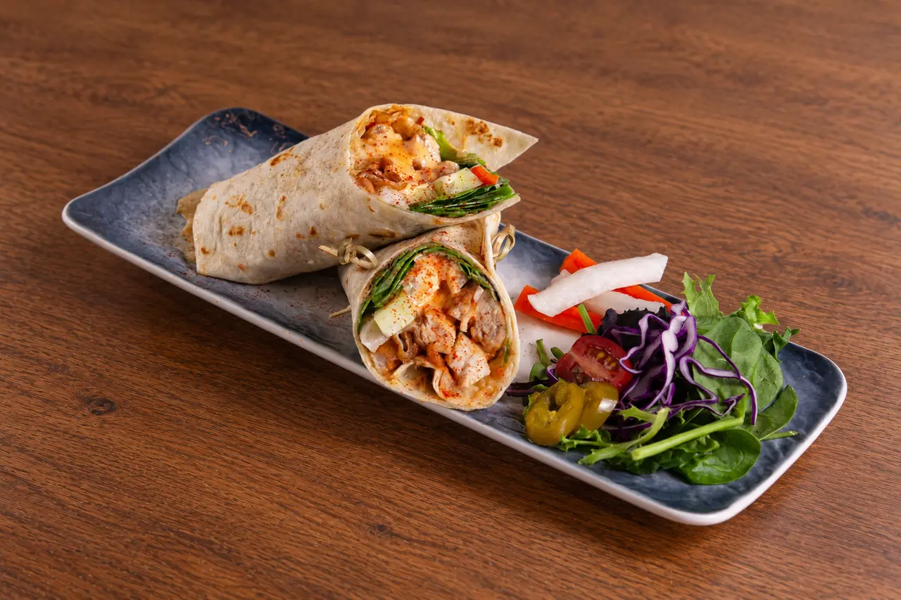 Two halves of the Panang chicken wrap with fresh vegetables.